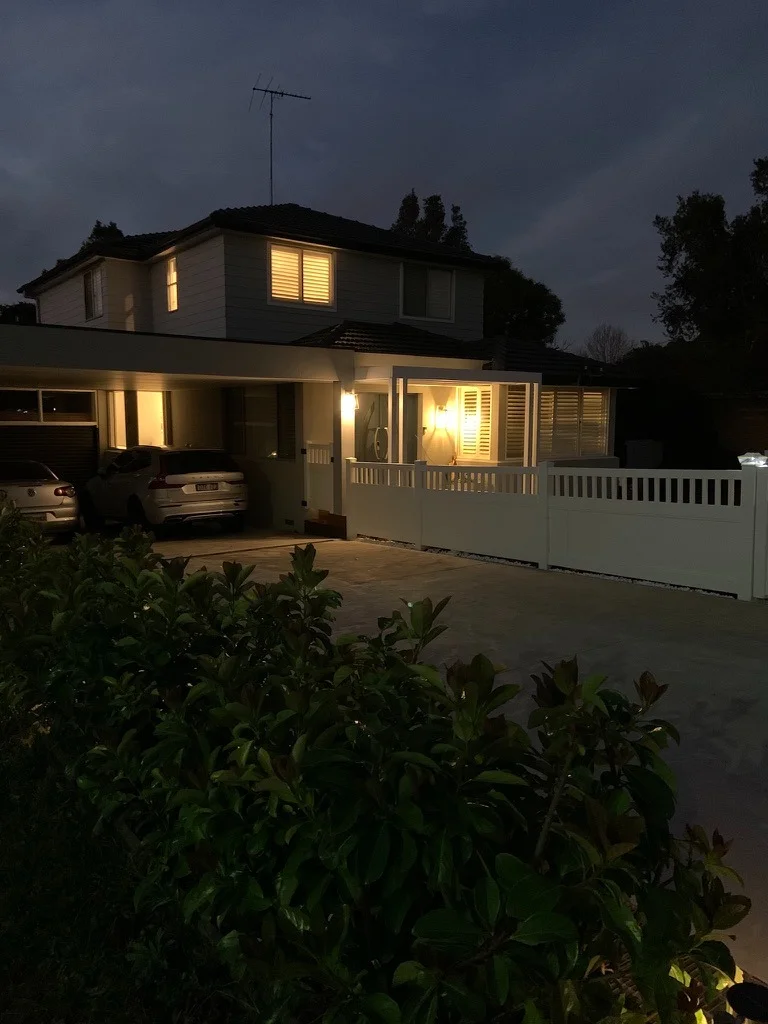 Completed facade at dusk — modern rendered exterior, lit garden bed and bespoke entrance